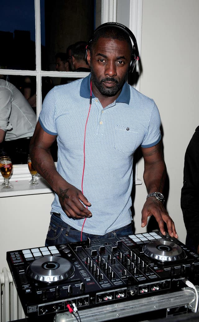Idris Elba mixing records while wearing headphones