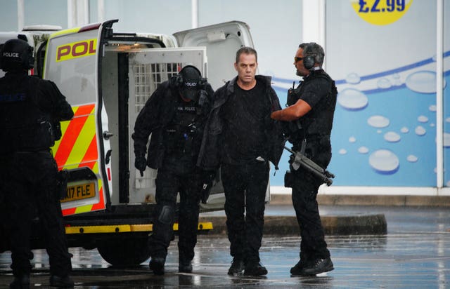 Armed police detain a man (centre) at the scene 