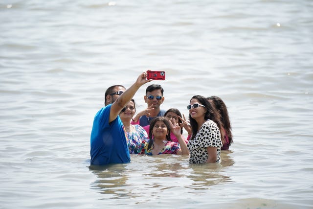 A man takes a family selfie in the water at Southend-on-Sea on the Thames Estuary in Essex 