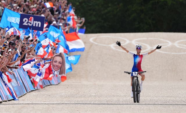 France's Pauline Ferrand-Prevot with her arms outstretched and off her handlebars celebrates winning gold.