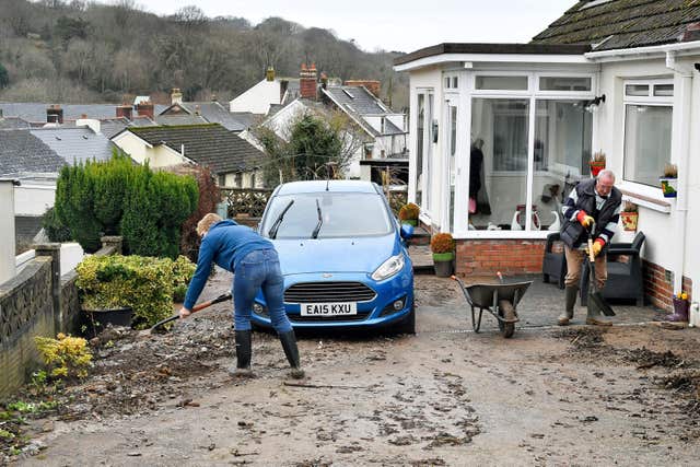 Paul and Lucy Davis clear silt and debris from their home on Corner Lane, Combe Martin, North Devon, after flooding affected parts of the South West (Ben Birchall/PA)