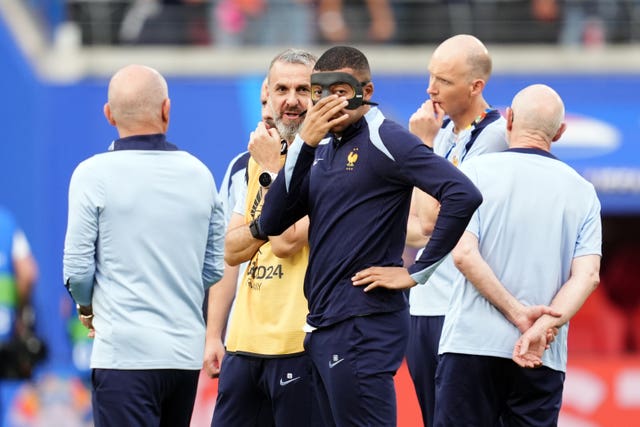 Kylian Mbappe, centre, with a protective mask on his face as he warms up before the UEFA Euro 2024 Group D match