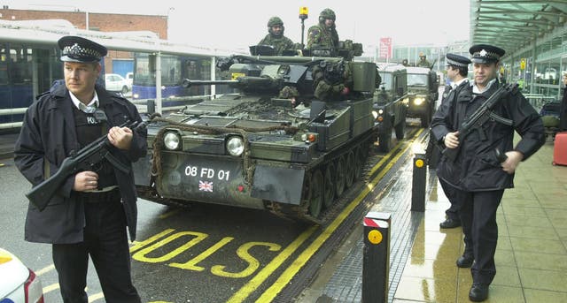 Two armed police officer and soldiers in an armoured car at Heathrow Airport