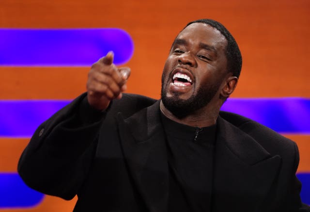 Sean Combs smiles and points