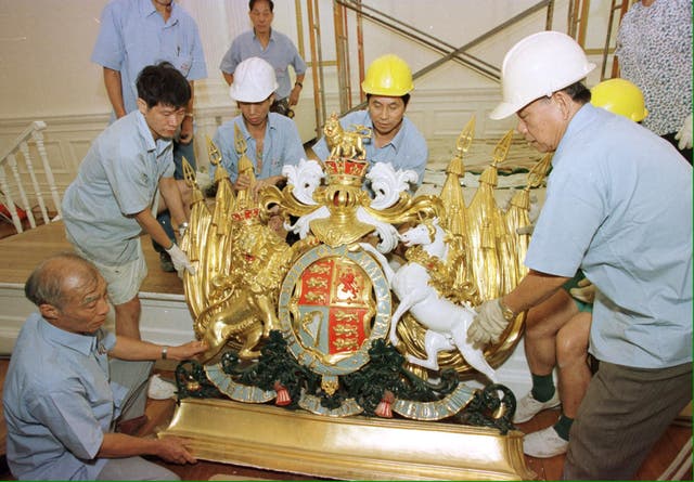 Workers remove the Royal Coat of Arms that adorn the ballroom at government house in Hong Kong ahead of the 1997 handover to China (Handout/PA)