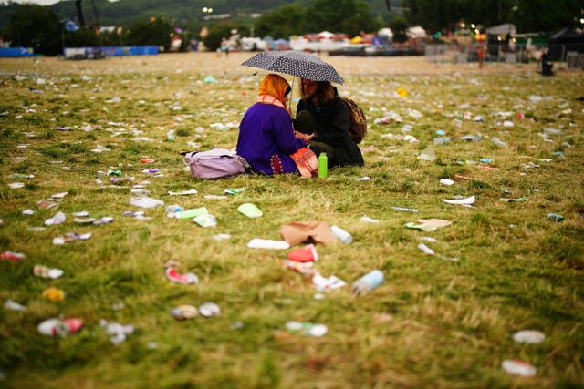 Festival goers sit amongst the waste