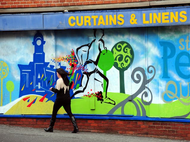 A woman walks past closed shops in Derby city centre (Rui Vieira/PA)
