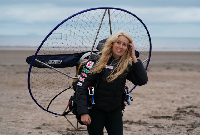 Sacha Dench smiling on a beach, wearing her paramotor on her back