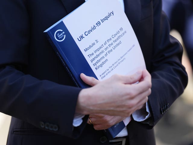 A person holds a copy of the UK Covid-19 Public Inquiry Module 3 Report outside Dorland House, London, following its publication
