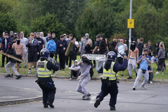 A youth throws a fence post towards police during an anti-immigration demonstration near the Holiday Inn Express in Rotherham, South Yorkshire