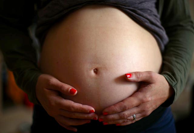 A pregnant woman holds her stomach