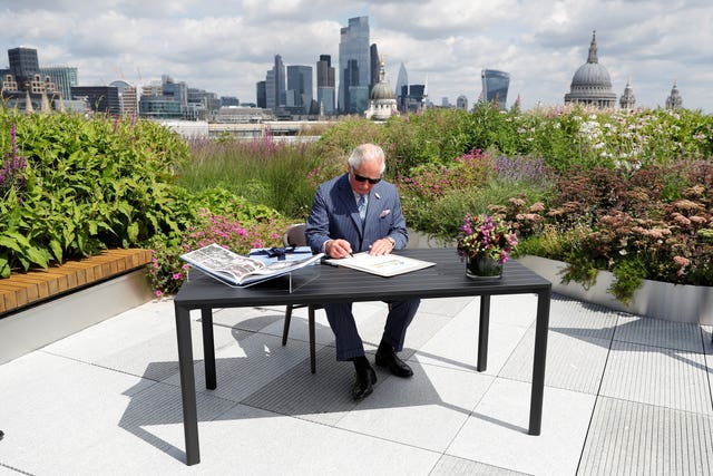 The Prince of Wales signs a document commemorating his visit to Goldman Sachs in central London