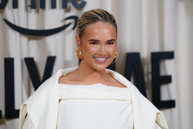 Molly-Mae Hague smiling while wearing a white dress at a red carpet event