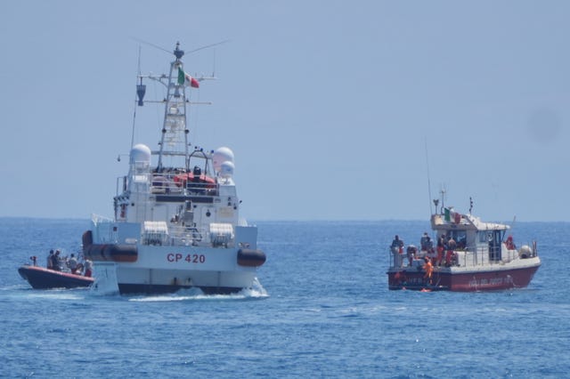 The Italian Coastguard boat on the water next to smaller boat of rescue team members