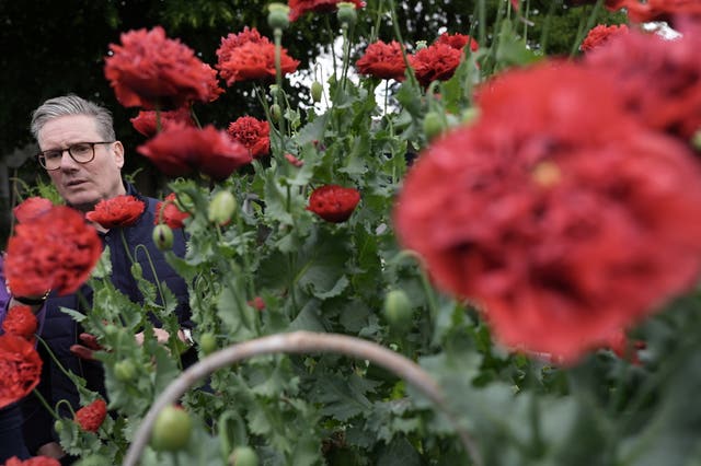 Labour Party leader Sir Keir Starmer inspects some red flowers during a visit to Harlesden Town Garden in north-west London