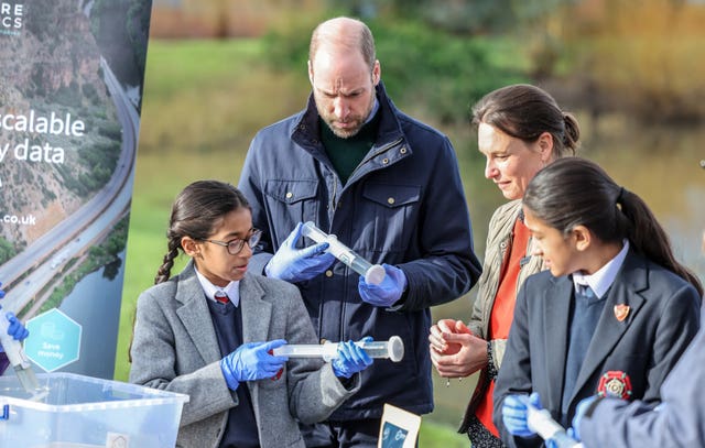 The Prince of Wales with local school children as they prepare to filter DNA samples through a syringe