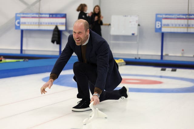 The Prince of Wales slides on the ice with a curling stone