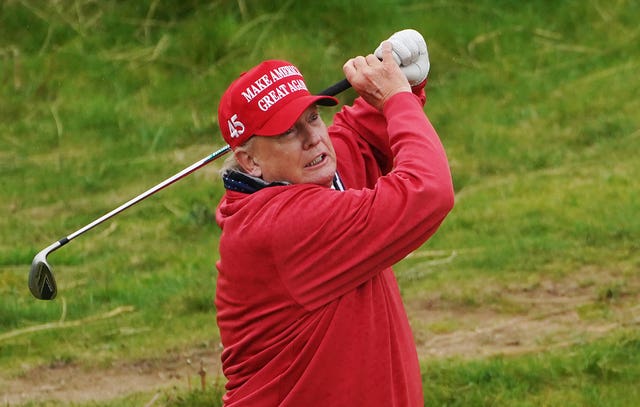 Donald Trump playing golf wearing a MAGA hat