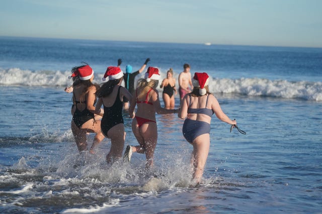 Swimmers wearing Father Christmas run into the sea