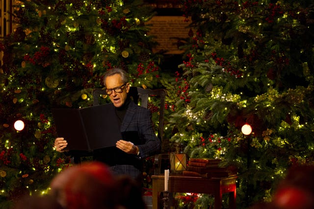 Richard E Grant in front of a Christmas tree