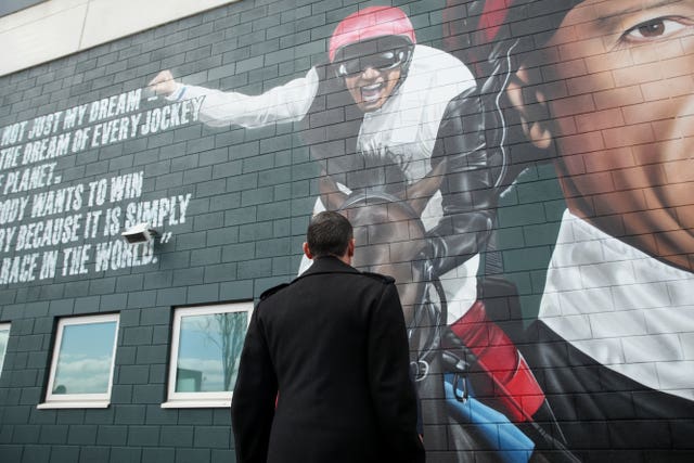 Frankie Dettori looks at a new mural of him unveiled at Epsom Downs Racecourse