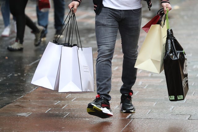 Legs of a male shopper walking while holding numerous bags