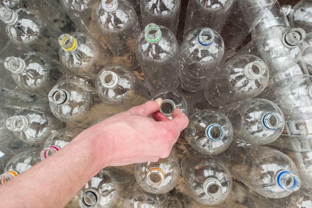 A person places plastic bottles in a row for recycling 