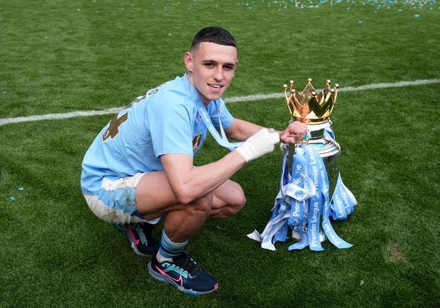 Manchester City’s Phil Foden celebrates with the Premier League trophy