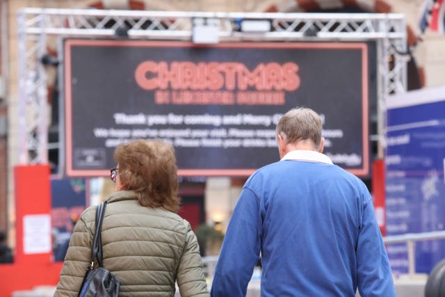 People walk past a large sign in London’s Leicester Square reading Christmas, as a rapid rise in Covid-19 cases has led to a surge in booking cancellations across the hospitality industry. Picture date: Thursday December 16, 2021.