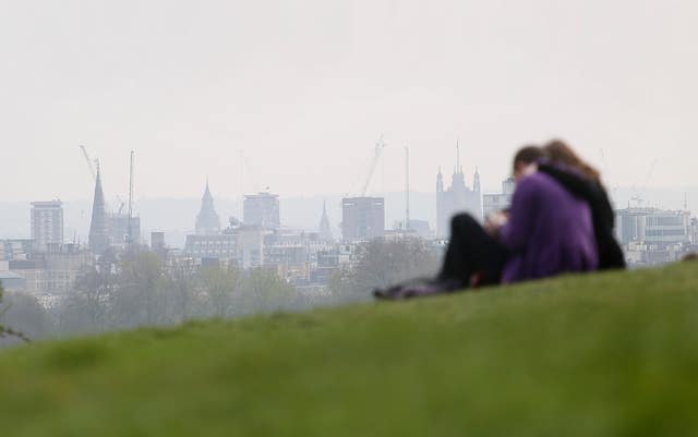 A couple sitting in Primrose Hill looking at smog over London (Philip Toscano/PA)