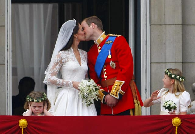 Prince William and his wife Kate Middleton kiss on the balcony as Grace van Cutsem covers her ears (Chris Ison/PA)