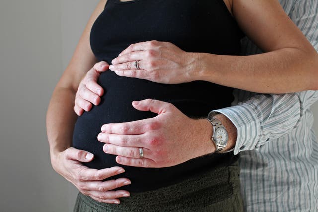 A man and a woman's hands on a pregnant woman's belly