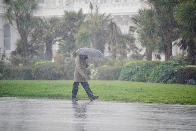 A person with an umbrella walking in heavy rain at Plymouth Hoe