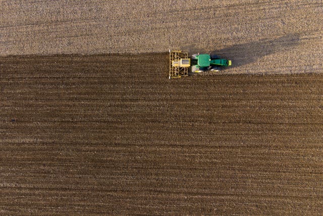 An aerial shot of a tractor drilling crops into a field 
