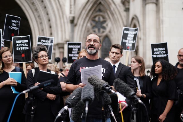 Andrew Malkinson speaking into several microphones outside court, surrounded by supporters