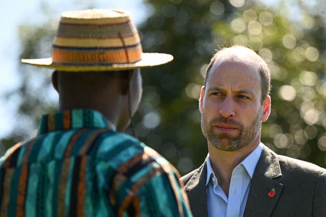 Prince of Wales talks to man in hat and striped shirt