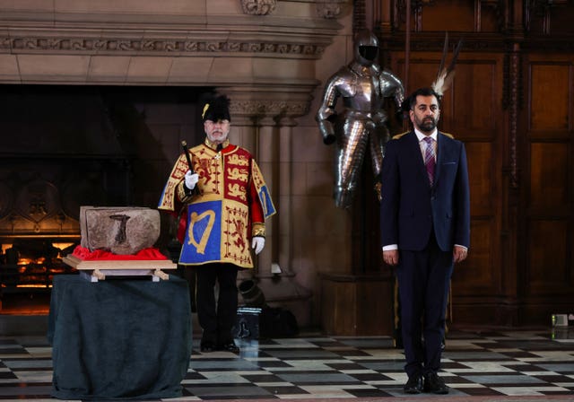 First Minister Humza Yousaf stands beside the Stone of Destiny 