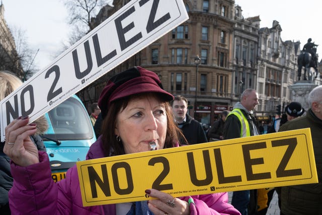 An anti-Ulez protester holds two registration plates: 