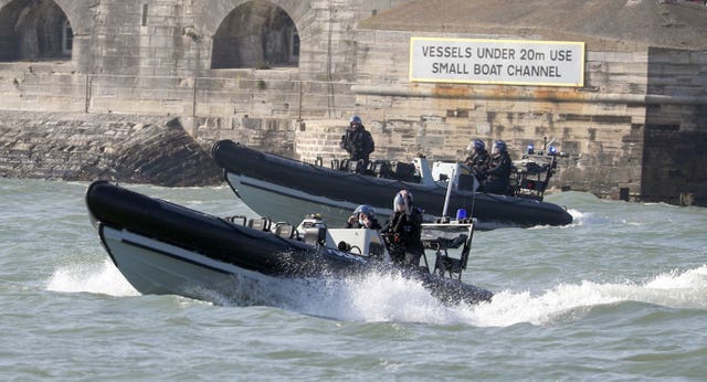 Police ribs escort the Royal Navy aircraft carrier HMS Queen Elizabeth leaves Portsmouth Naval Base in Hampshire as it sets sail for exercises at sea 