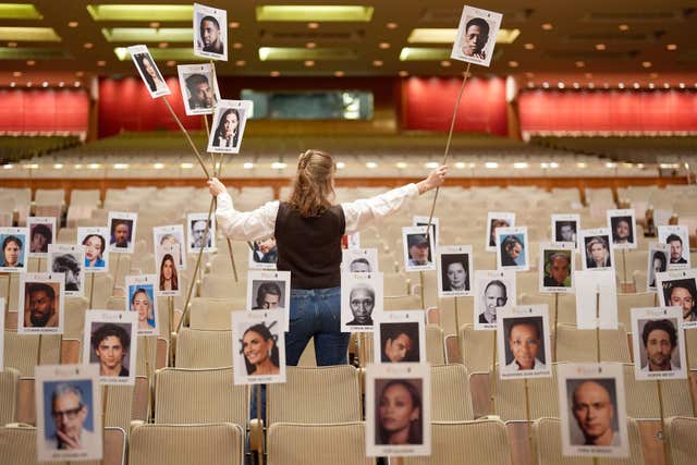 Pictures of heads on sticks are arranged on chairs