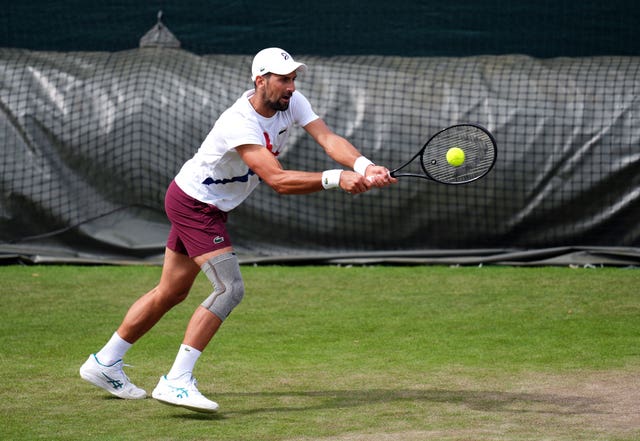 Novak Djokovic hits a backhand wearing strapping on his knee