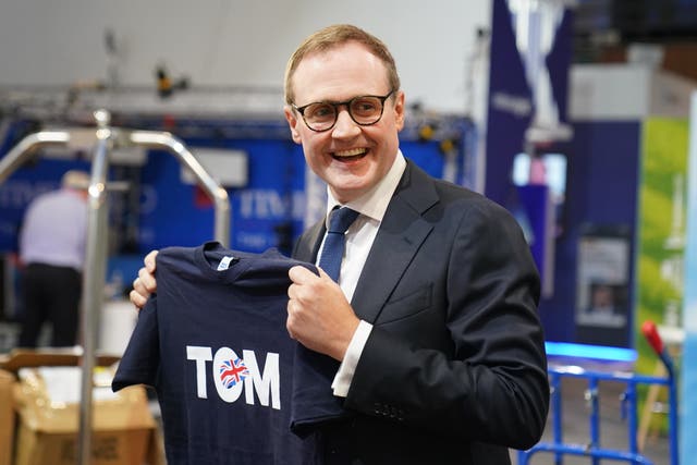 Tom Tugendhat holding one of his leadership campaign T-shirts. It is blue, with the word 'TOM' and a union jack on the front