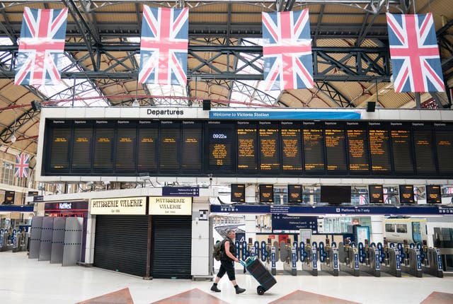 A man passes departure boards at Victoria station in London