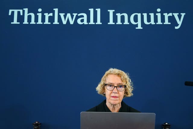 A woman sits under a sign reading Thirlwall Inquiry