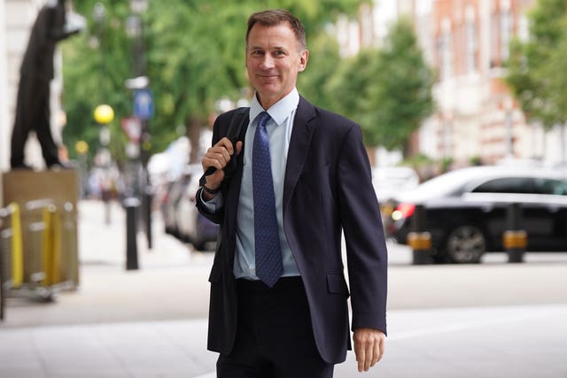 Jeremy Hunt, backpack slung over his right shoulder, smiles as he arrives at the BBC's Broadcasting House for an appearance on Sunday with Laura Kuenssberg