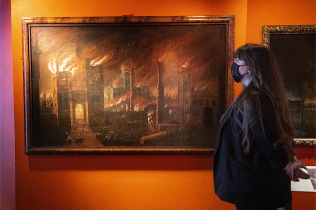 A woman looks at a painting of the Great Fire of London