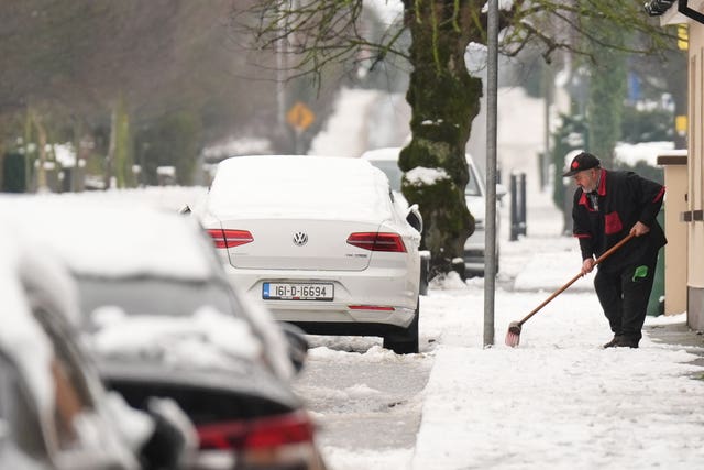 A man clears snow from the pavement in Ballylynan in County Laois