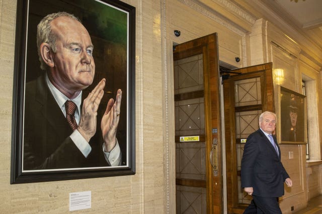 Former taoiseach Bertie Ahern passing between portraits of former deputy first minister Martin McGuiness (left) and former first minister Ian Paisley (right) at Stormont, 