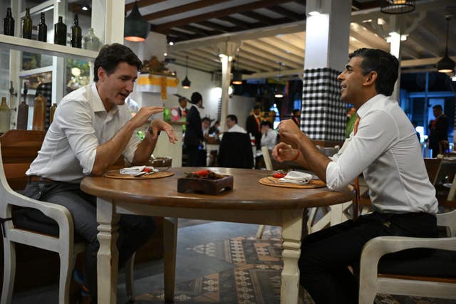 Canada’s Prime Minister Justin Trudeau and Prime Minister Rishi Sunak sit at a table 