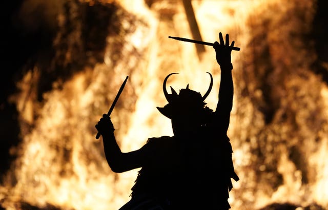 A member of the Pentacle Drummers performs in front of a burning wicker man during the Beltain Celtic Fire Festival